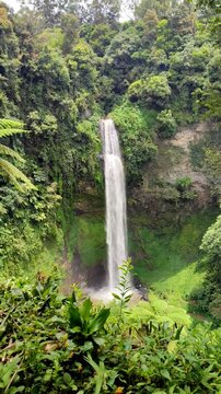 Curug Cimahi or Cimahi Waterfall, Indonesia, surrounded by lush green trees.