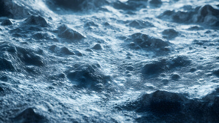 Fototapeta premium Close-up view of a rugged, icy, or rocky terrain. The surface is textured with numerous craters and uneven formations, lit with a cool, bluish light. A desolate, extraterrestrial landscape.