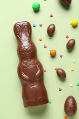Chocolate Easter bunny with eggs and sprinkles on green background
