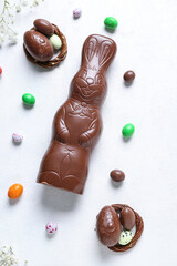 Chocolate Easter bunny with eggs and flowers on white background