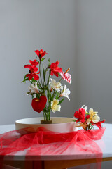 Beautiful ikebana with red veil on dining table in room