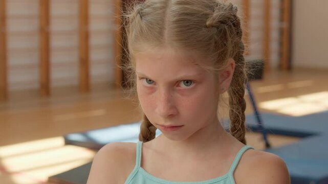 Angry girl looking at camera close up sad frustrated offended child kid pupil student annoyed schoolgirl in gym upset irritated grumpy daughter sport gymnast little sportswoman offense school problem