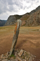 An ancient stone idol tilted by time in the middle of a wide clearing at the foot of a mountain...