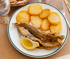 Hake by rustically frying and served with boiled potatoes and lemon