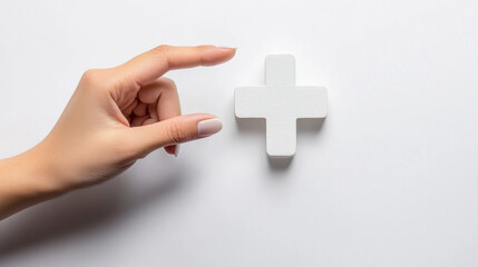 Obraz premium Hand Reaching for a White Plus Symbol on a Clean Surface