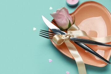 Table setting for Valentine's Day with pink rose and hearts on blue background