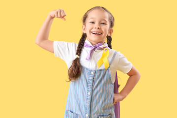 Cute little girl in superhero costume with yellow ribbon on color background. Childhood cancer awareness concept © Pixel-Shot