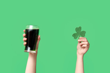 Hands with beer and clover on green background. St. Patrick's Day celebration