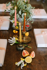 Festive table setting with candles, fruits, and greenery for a special gathering in a cozy atmosphere