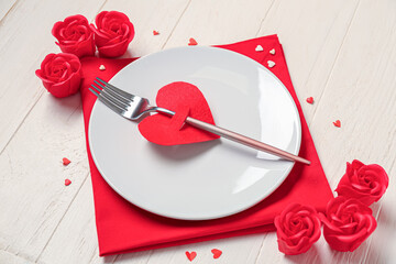 Beautiful table setting for Valentine's Day with decorative roses and hearts on white wooden background