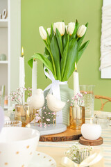 Beautiful table setting with burning candles and tulip flowers for International Women's Day celebration in living room