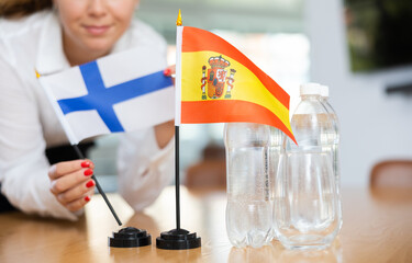 Little flag of Spain on table with bottles of water and flag of Finland put next to it by positive...