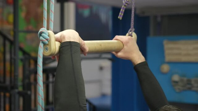 Caucasian man doing pull-ups on trapeze. Warm-up before the climbing wall. 