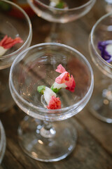 Colorful edible flowers in elegant glass dessert cups on a rustic wooden table setting for a special occasion