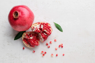 Fresh ripe pomegranates with seeds and leaves on white background