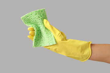 Female hand with rag on grey background. Mold removal concept