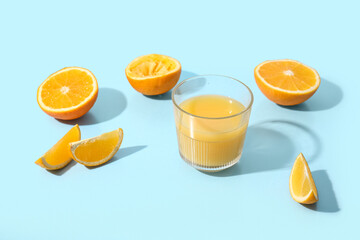 Glass of fresh orange juice and fruits on blue background