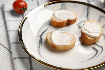 Plate of tasty bruschetta with processed cheese and fresh tomato on white wooden background, closeup