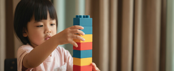 A young girl is playing with a stack of colorful legos