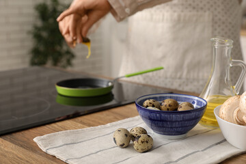 Woman frying quail eggs on stove in kitchen