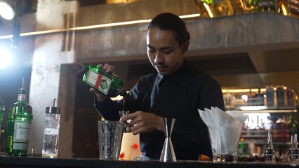 Asian bartender pouring mixed cocktail juice liqueur all ingredient into sliver shaker alcohol drink, making special advertisement creative tasty, focused refreshing showcase at bar luxury. Vinosity.