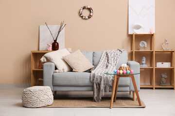 Interior of living room with sofa, Easter cake and eggs on table