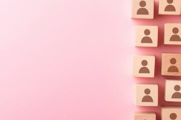 Minimalist network of people icons on wooden blocks against pink background, symbolizing connection and community