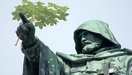 Fototapeta premium Statue points skyward with branch, outdoor monument
