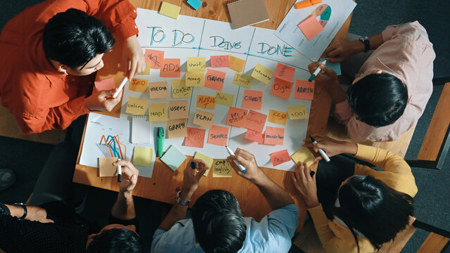 Top view of people writing and making scrum task board while writing marketing and planning strategy at colorful sticky notes. Smart team manage work performance by using kanaban board. Convocation.