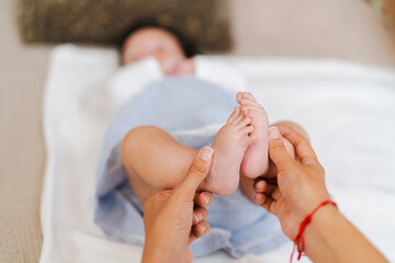 Mother playing with baby's feet, stimulating and bonding through loving touch