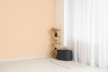 Pouf with shelf unit near light curtain in room