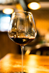 A wine glass is filled with red wine on a dinner table.