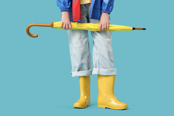 Teenage girl in gumboots with umbrella on blue background