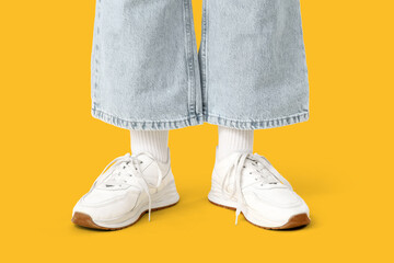 Teenage girl in sneakers on yellow background, closeup