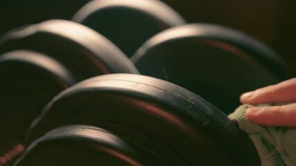 Hand Cleaning Dusty Dumbbells with Cloth in Home Gym - Fitness Equipment Maintenance Closeup in Warm Lighting