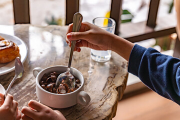 A little boy is eating his breakfast, a bowl of chocolate flavored cereal with fresh milk