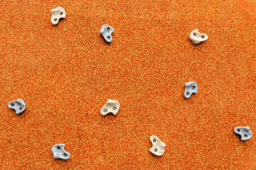 multiple climbing grips, securely bolted onto the rough, rubberized wall, arranged in a scattered pattern, outdoor playground for kids