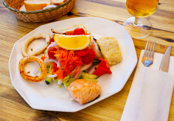 Fresh vegetable salad served with grilled squid rings and fish steaks. Healthy seafood dinner