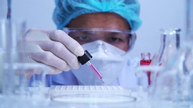 scientist dropping biochemical solution in to microplate for DNA analysis.