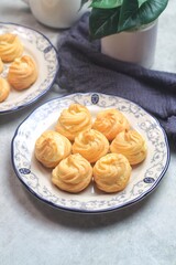 Kue Sus Isi Vla or soes cake (Choux Pastry Cream Puff) is Crispy and airy choux pastry shell are filled with smooth and soft custard cream. served in a plate.

