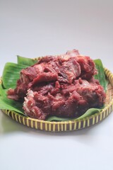 Raw meat or daging kurban in bamboo tray isolated on white background, from Moslem Halal Slaughtering during Eid Al-Adha Al Mubarak,
