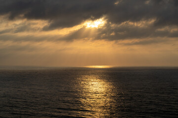 Dark cloudscape over the vast ocean with calm and sparkling reflections on the water.