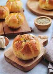 Korean Garlic and Cheese Bread (Yugjjog Maneulppang) is Popular Street Food in Korea. Made from Bread Bun, Cream Cheese, Garlic, Oregano and Honey. Isolated on wodden bowl. Warm ton
