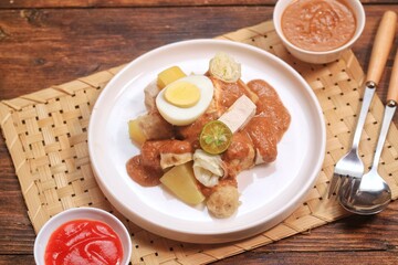 Siomay is one of popular dish from Indonesia that made from fish dumpling, potato, boiled egg with peanut sauce served at  white plate. 

