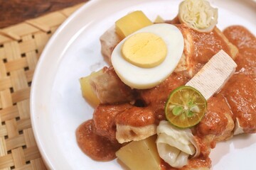 Siomay is one of popular dish from Indonesia that made from fish dumpling, potato, boiled egg with peanut sauce served at  white plate. 
