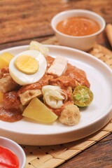 Siomay is one of popular dish from Indonesia that made from fish dumpling, potato, boiled egg with peanut sauce served at  white plate. 
