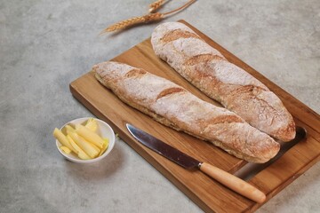 fresh cut baguettes on the wodden tray with butter. sourdough baguettes. healthy food.
