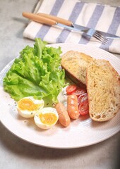 Sourdough bread open faced sandwiches with lettuce, tomatoes, egg and sausage. A healthy and delicious breakfast.
