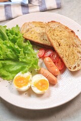 Sourdough bread open faced sandwiches with lettuce, tomatoes, egg and sausage. A healthy and delicious breakfast.

