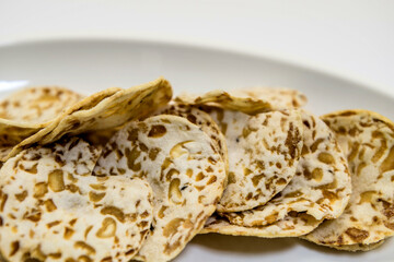 High fiber tempeh chips on serving dish against white background.